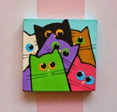 there are many different colored cats painted on this square piece of wood that is mounted to the wall