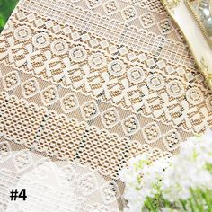 the table cloth has been made with crocheted lace and is next to some flowers