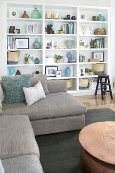 a living room filled with lots of furniture and bookshelves on top of white shelves