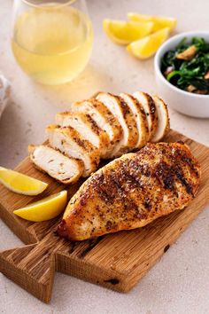 sliced chicken on a cutting board with lemons and spinach