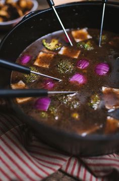 a pan filled with soup and broccoli on top of a table