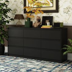 a black dresser sitting in front of a wall with a painting on top of it