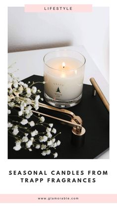 a candle sitting on top of a black tray next to flowers and a gold pen