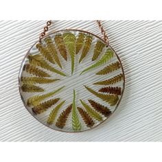 a glass pendant with green and brown leaves on it