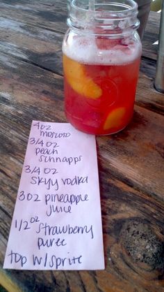 a jar filled with liquid sitting on top of a wooden table next to a paper