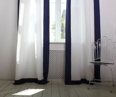 a white chair sitting next to a window in a room with blue and white curtains