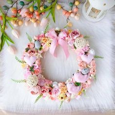 a wreath with pink flowers and hearts on it, surrounded by other items such as candles