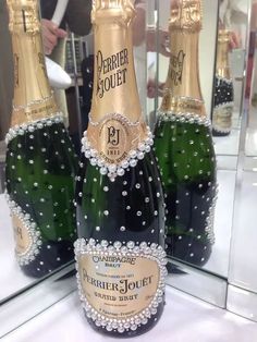 three bottles of champagne sitting on top of a table next to each other in front of a mirror