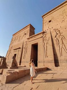 a woman standing in front of an egyptian temple