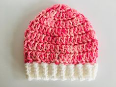 a crocheted pink and white hat sitting on top of a table