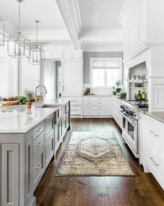 a large kitchen with white cabinets and wood flooring, along with an area rug