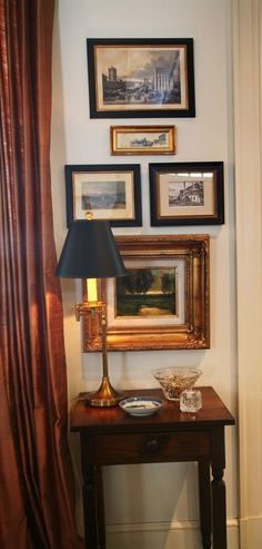 a table with a lamp and pictures on the wall