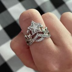 a woman's hand holding a diamond ring on top of a checkered table