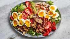 a plate filled with meat, eggs and vegetables on top of a marble countertop