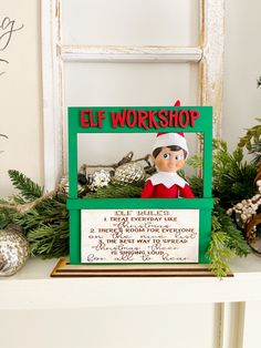 an elf's workshop sign on top of a shelf with christmas decorations and ornaments