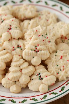 white cookies with sprinkles are on a christmas plate, ready to be eaten