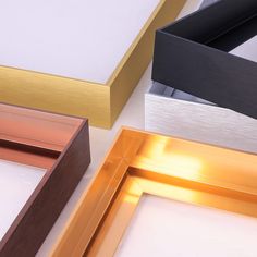 four different colored frames sitting next to each other on a white surface with gold and silver trim