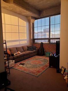 a living room filled with furniture next to a large window covered in sunlight from the windows