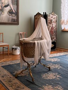 a baby crib in a living room with paintings on the walls and rugs