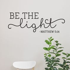 a wall decal with the words be the light and a potted plant next to it