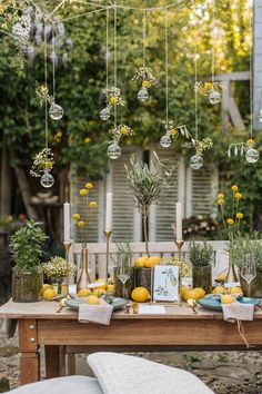 an outdoor table with lemons and greenery on it, hanging from the ceiling