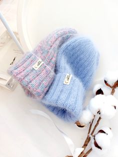 a blue and pink hat sitting on top of a white plate next to cotton flowers