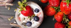 yogurt with strawberries, blueberries and sunflowers on a wooden table