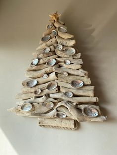 driftwood christmas tree with seashells and starfish on the top, against a white wall