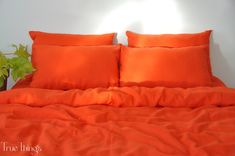 an orange bed with two pillows and a plant