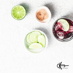 three glasses filled with different types of drinks and garnished with limes, red onions, and ginger seeds