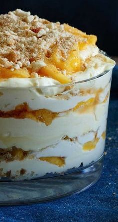 a layered dessert in a glass dish on a blue cloth