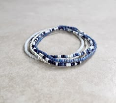 "This is a beautiful size 11/0 Japanese Bliss stretch seed bead bracelet set! You'll receive 5 bracelets in this set that include matte white, dark opaque navy/touch of purple tone, matte silver, and a shade of matte wispy lavender/blue. These seed beads are size 11/0 so they're super tiny, and the beautiful colors of the seed beads I use are stunning! If you're unfamiliar with the size \"11/0\" the hole is the size of a needle point! (11/0 seed beads are 2mm by 2mm with the hole a diameter of 1mm.) Stretch seed bead bracelets are made on elastic cord, so these bracelets stretch then slide over your hand! It's your choice of how you'd like your bracelets to fit based on your wrist size, and the size options given! (Please measure your wrist accordingly!) Your bracelets will come shipped in Seed Bead Bracelet For Men, Bracelet Ideas Tiny Beads, Mens Seed Bead Bracelet, Dark Blue Beaded Bracelet, Blue And Purple Bracelet, Seed Bead Bracelet Sets, Blue Seed Bead Bracelet, Seed Bracelets, Dark Bracelet