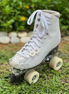 a pair of roller skates sitting on top of green grass and flowers in the background