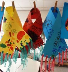 several colorful kites hanging from clothes pins with writing on them in the shape of animals