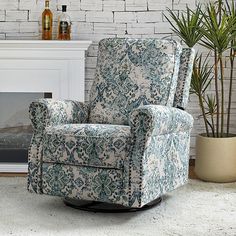 a chair sitting in front of a fireplace next to a potted plant