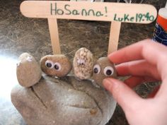 a hand is holding some rocks with eyes on them and a sign that says hosanna like me