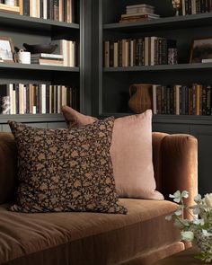 a living room filled with lots of bookshelves covered in brown and pink pillows