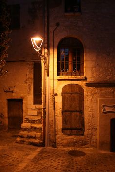 an empty street at night with a lamp post and steps leading up to the building