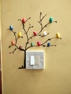 a light switch with colorful birds on it and a tree made out of small branches