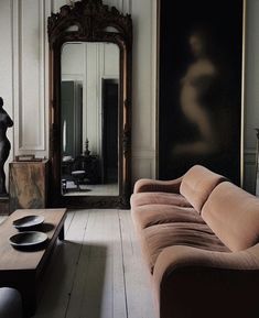 a living room filled with furniture next to a tall mirror and a statue in the corner