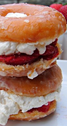 three donuts stacked on top of each other with cream and strawberries in the background