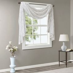 an image of a living room window with curtains on the windowsill and flowers in vases