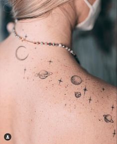 the back of a woman's neck with planets and stars tattooed on her shoulder