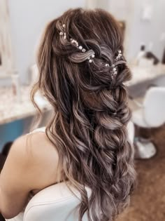 the back of a woman's head with long hair and flowers in her hair