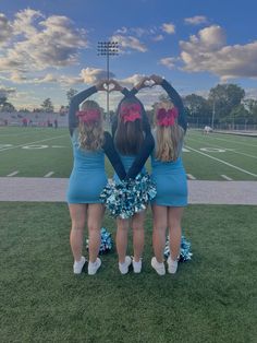 three girls in cheerleader outfits are standing on the field