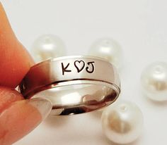 someone is holding their wedding ring with the word love written on it and pearls scattered around