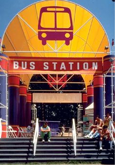 people are sitting on the steps under a bus station sign that reads, bus station