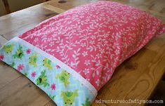 a pink and green pillow sitting on top of a wooden table