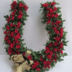 red roses arranged in the shape of a letter o with green leaves and gold ribbon