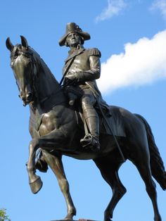 a statue of a man riding on the back of a horse in front of a blue sky